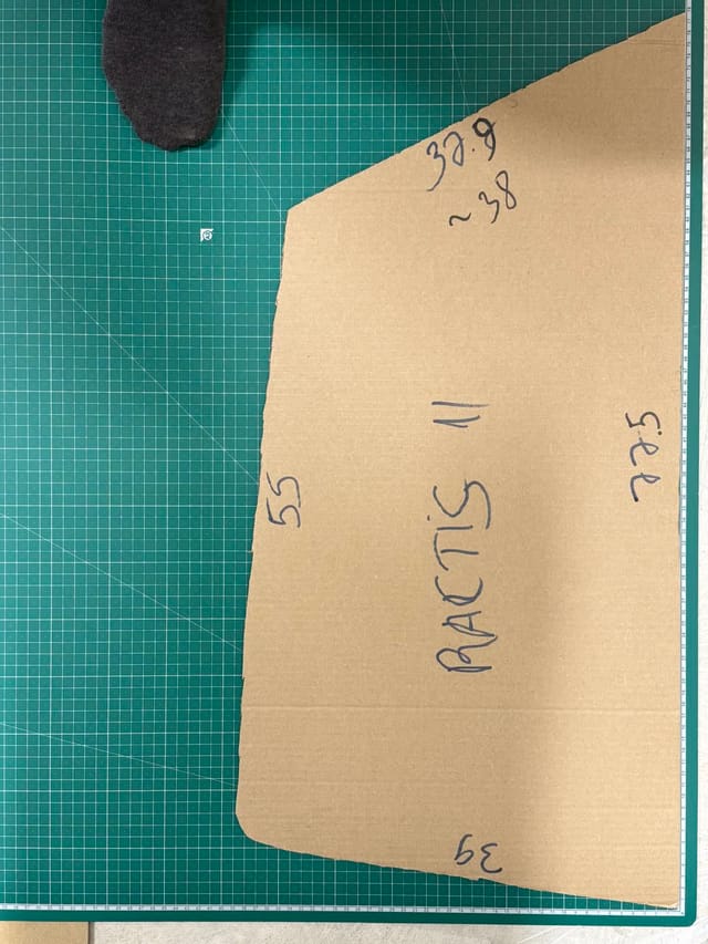 A hand-cut cardboard template for a specific vehicle's window